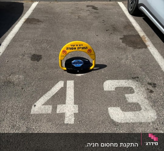 מחסום חניה צהוב עם כיתוב בעברית